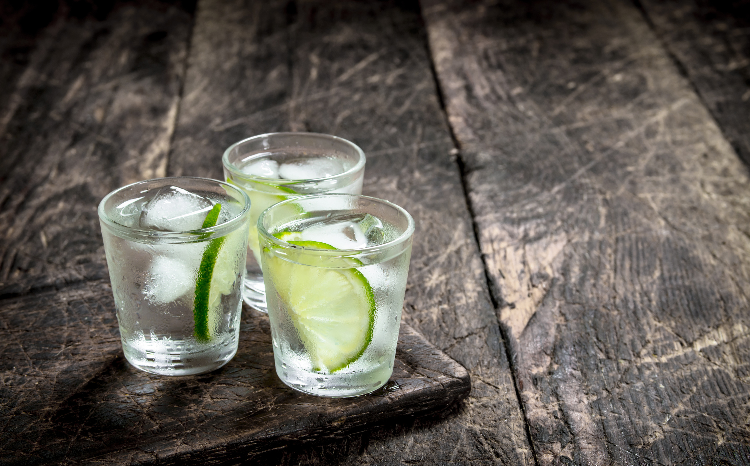 Vodka Shots with Lime and Ice on Wooden Board 